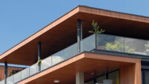 Modern huis met houten gevelbekleding en glazen balustrades, waarbij bitumen dé oplossing is voor een waterdicht dak